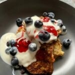 Banana and oat hotcakes with greek yoghurt, berries and raspberry jam drizzled over the top