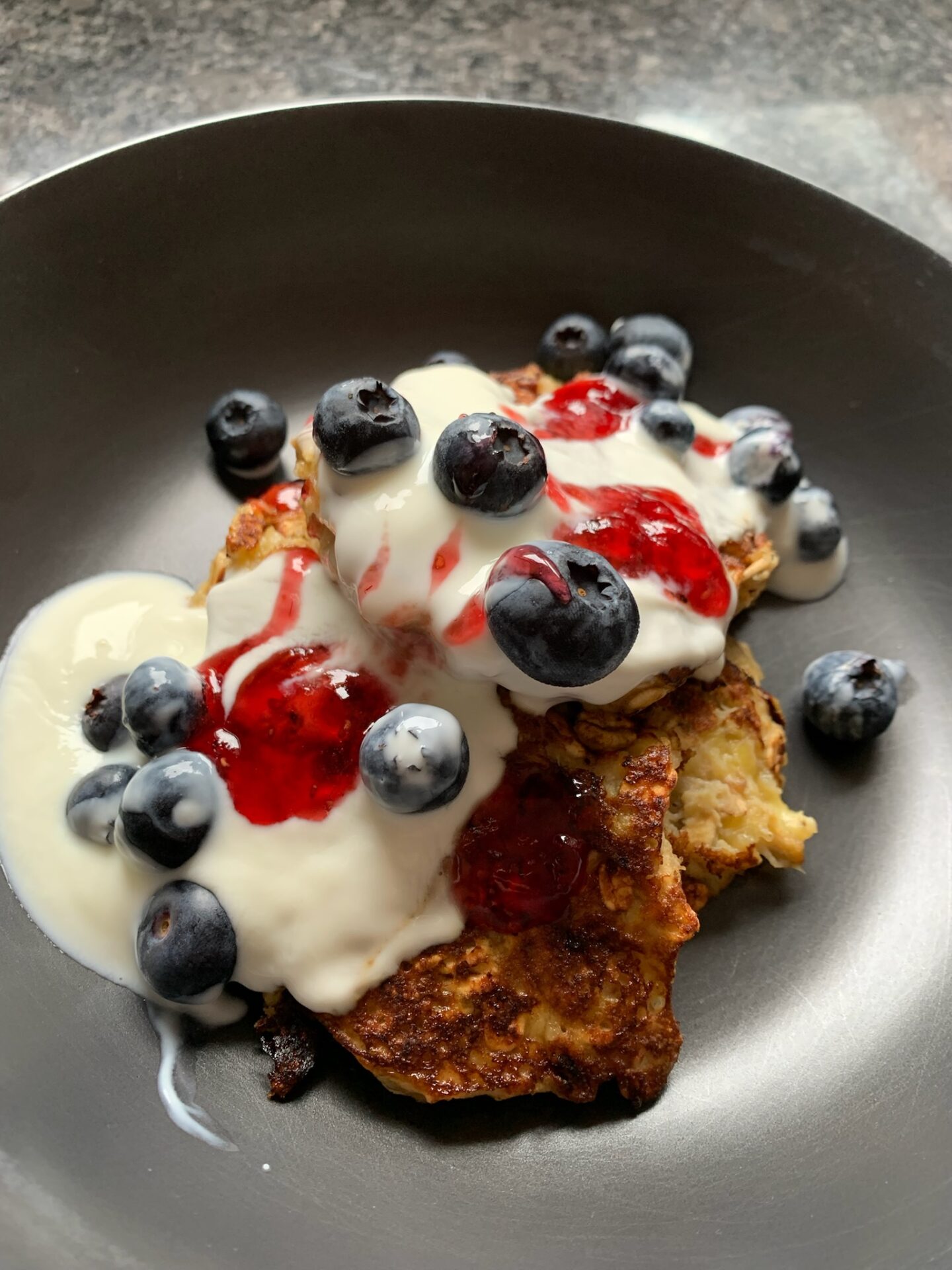 Banana and oat hotcakes with greek yoghurt, berries and raspberry jam drizzled over the top